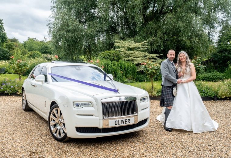 Scottish couple posing with a Rolls-Royce Ghost on their wedding day
