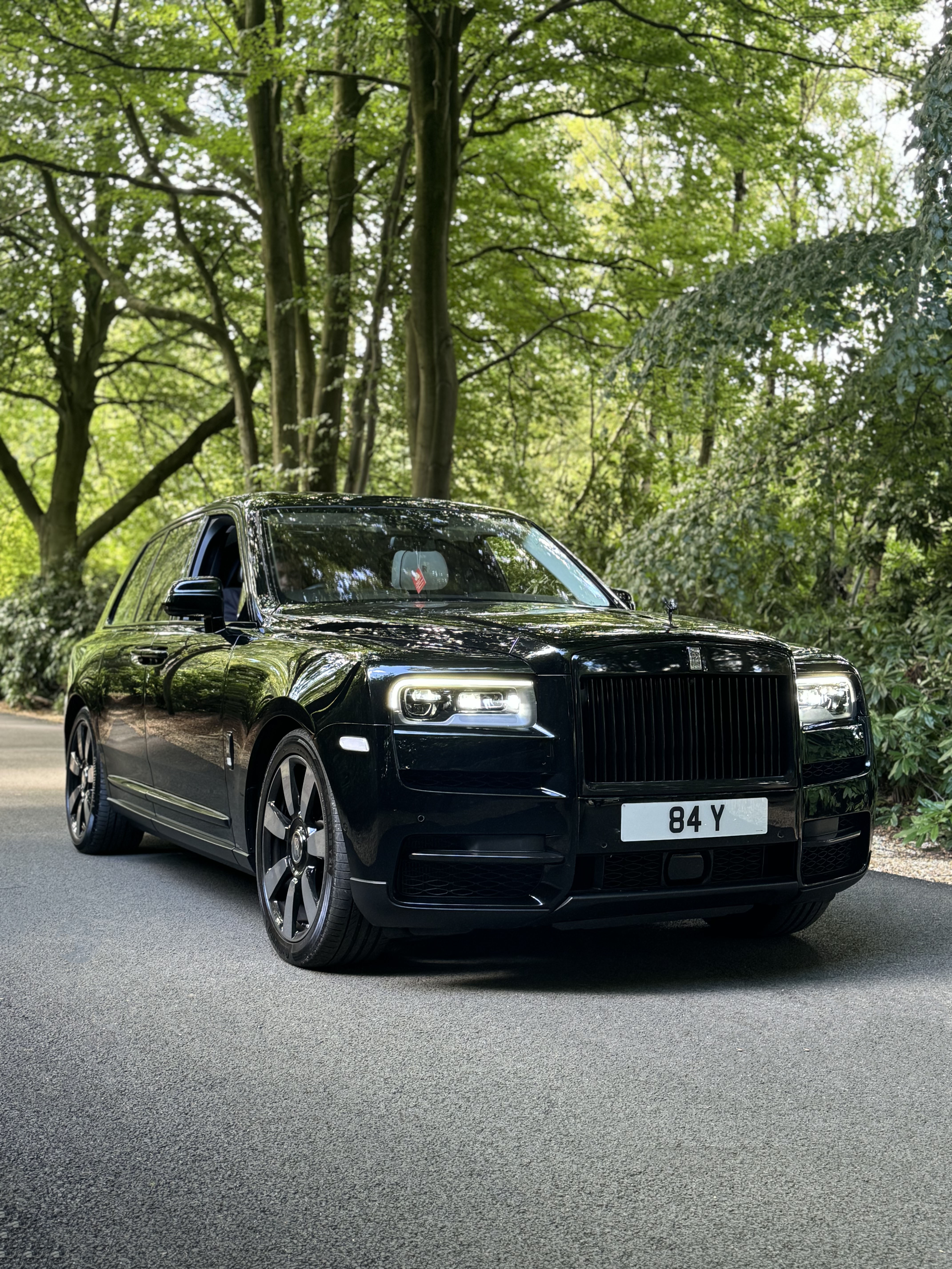 Black Cullinan wedding car on a road surrounded by trees