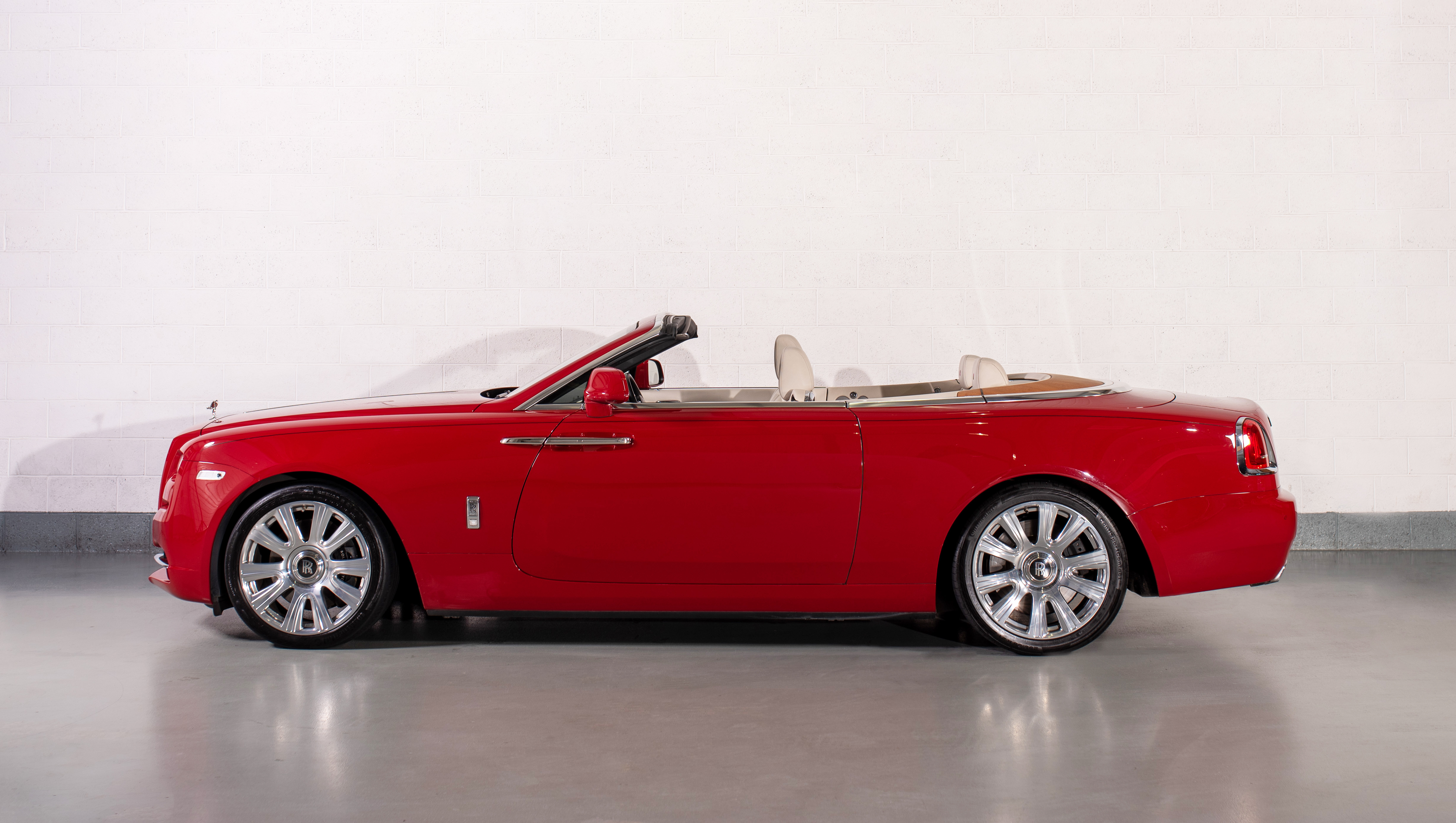 Side view of a Rolls-Royce Dawn in Ensign Red, parked in a showroom