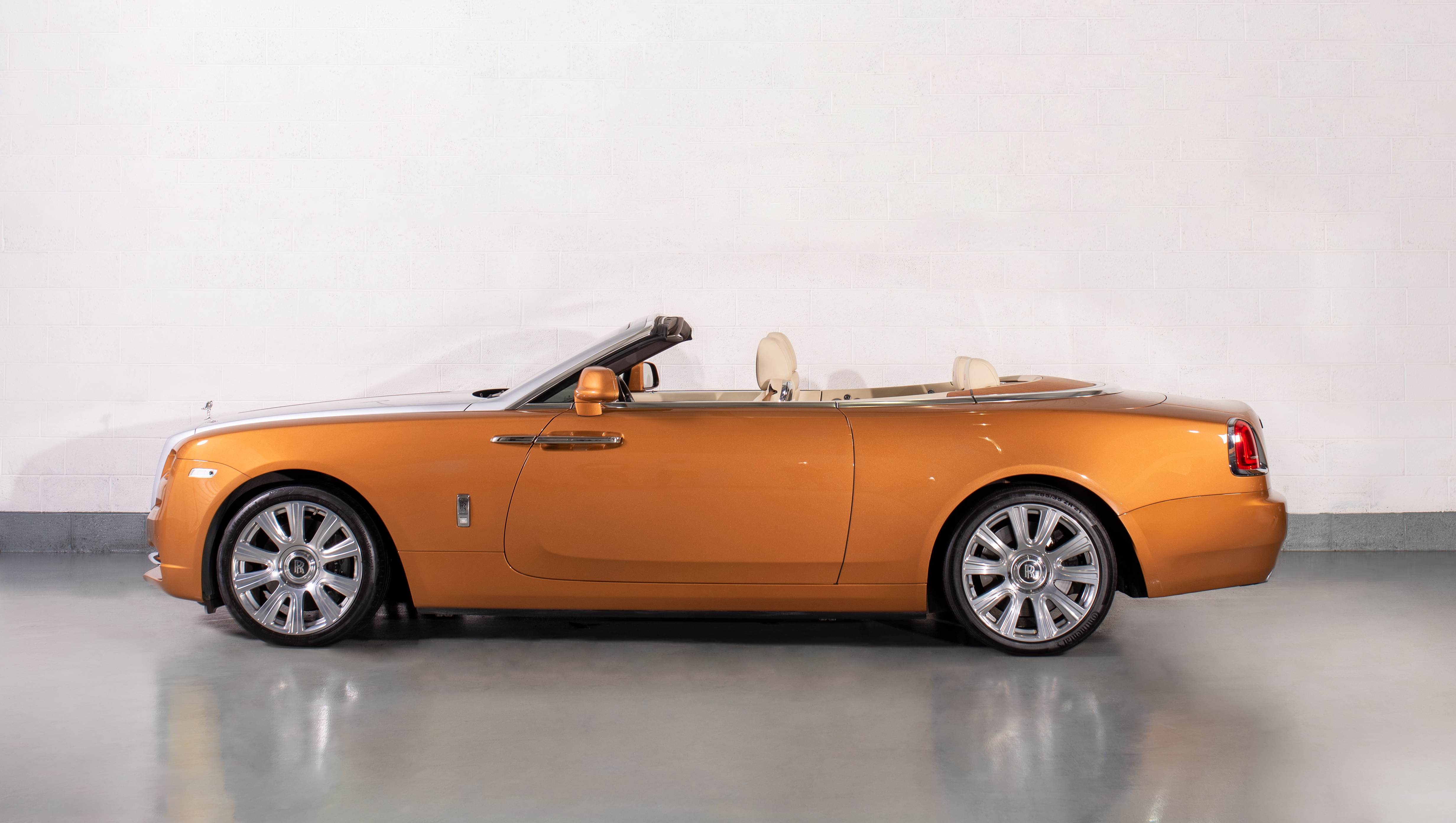 Side view of a Rolls-Royce Dawn in Tuscan Sun, parked in a showroom