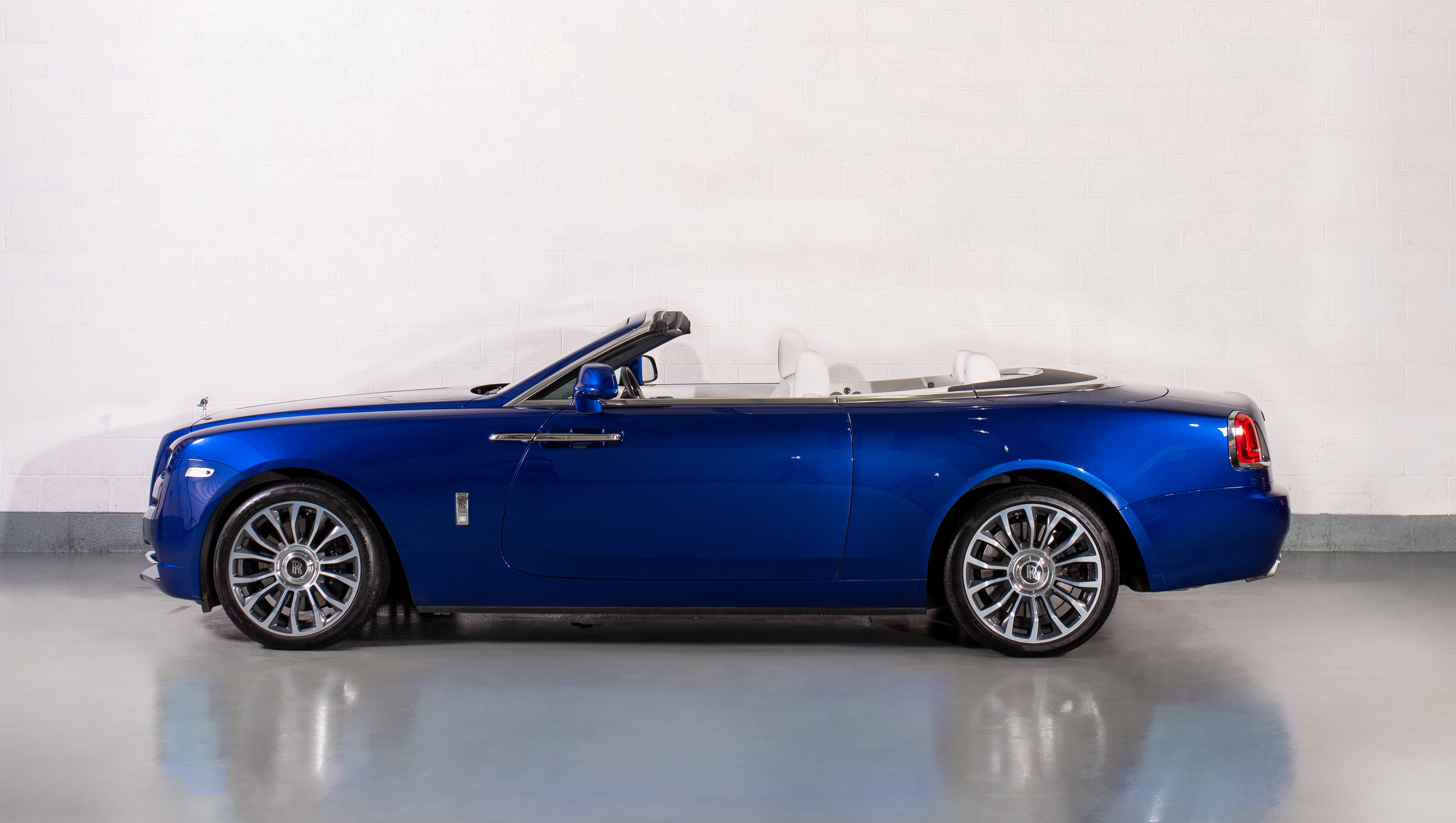 Side view of a Rolls-Royce Dawn in Miami Blue, parked in a showroom