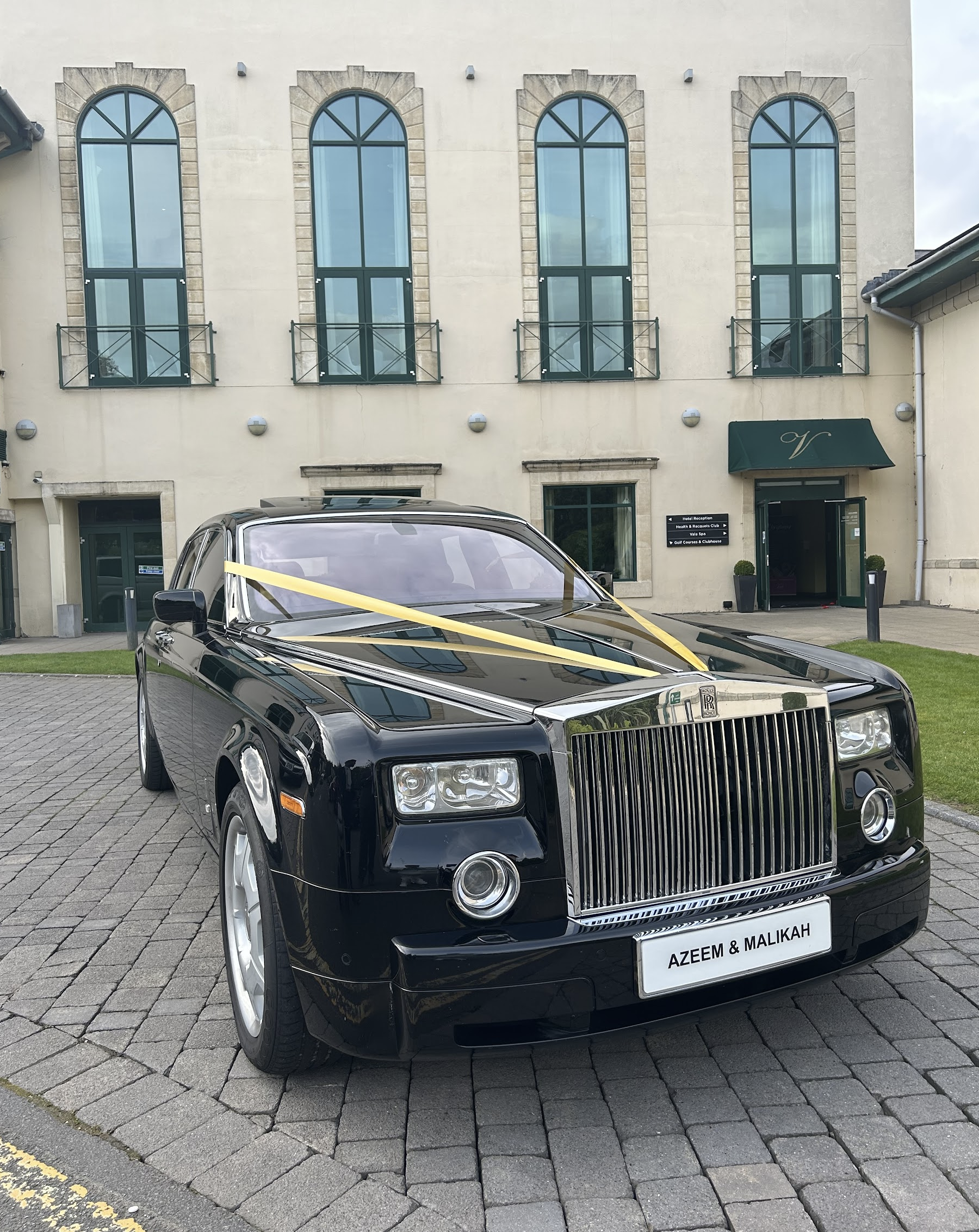 modern black Rolls-Royce Phantom wedding car outside hotel